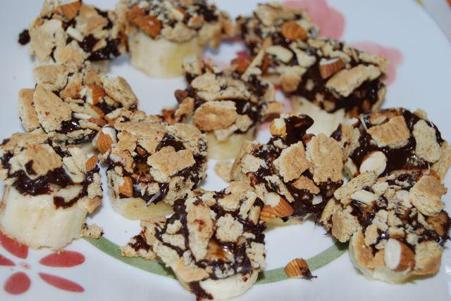 Banana slices dipped in chocolate and topped with almonds and graham crackers make a delicious, healthy, kid-friendly snack!