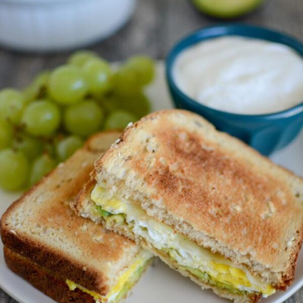 Microwave Egg Sandwich with avocado and cheese and grapes and yogurt on the side