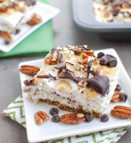 These Banana Cream Pie Bars are a fun twist on the traditional. Made with a 3 ingredient no-bake crust, fresh bananas & lots of chocolate, peanut butter and pecans, they're sure to be a hit dessert!