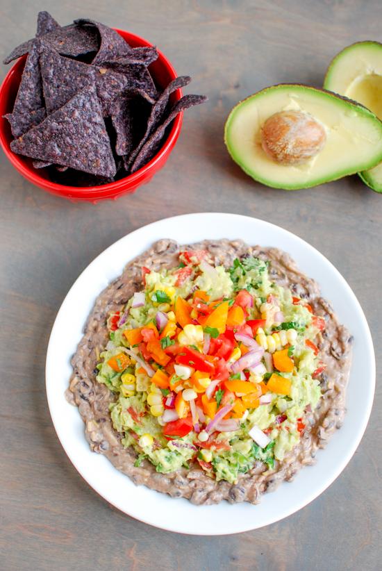 This Mexican Layer Dip is easy to make and full of flavor! With layers of spicy black bean dip, homemade guacamole and fresh corn salsa it's the perfect party appetizer or snack!