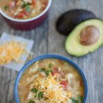 Two bowls of white chicken chili with an avocado and cheese and cilantro