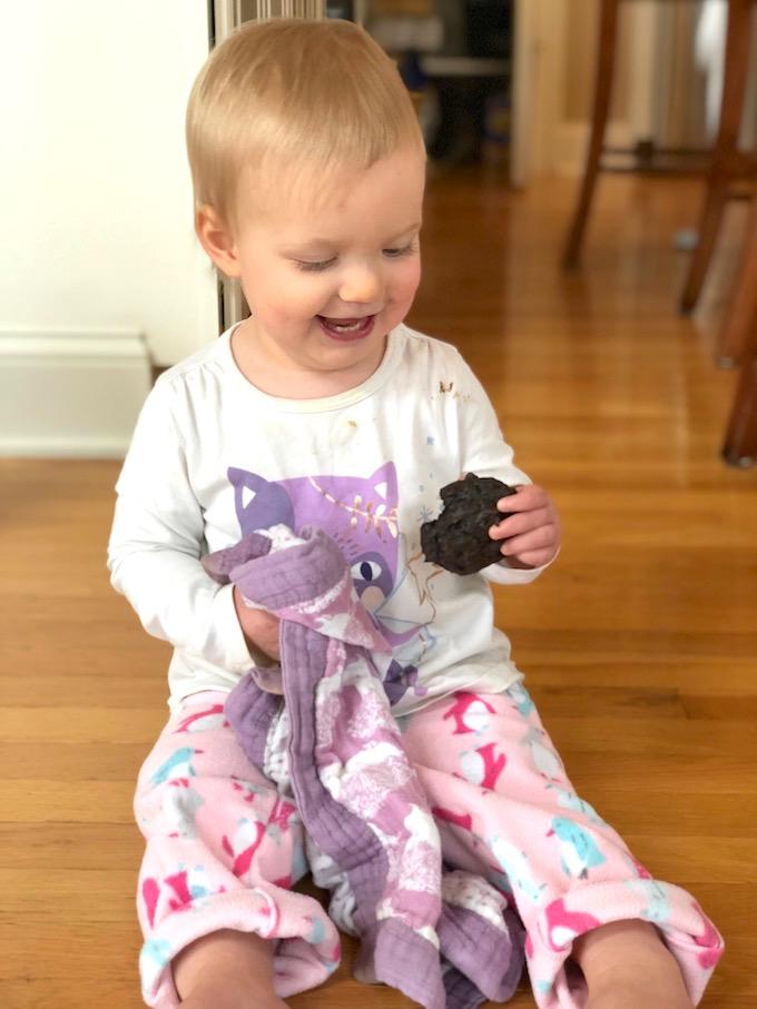 toddler eating chocolate pea cookie with blankie