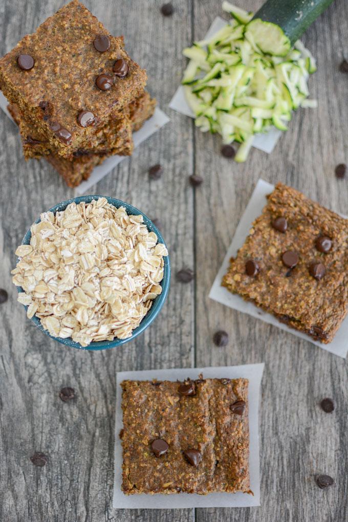 overhead shot of zucchini oat bars with bowl of oats and shredded zucchini