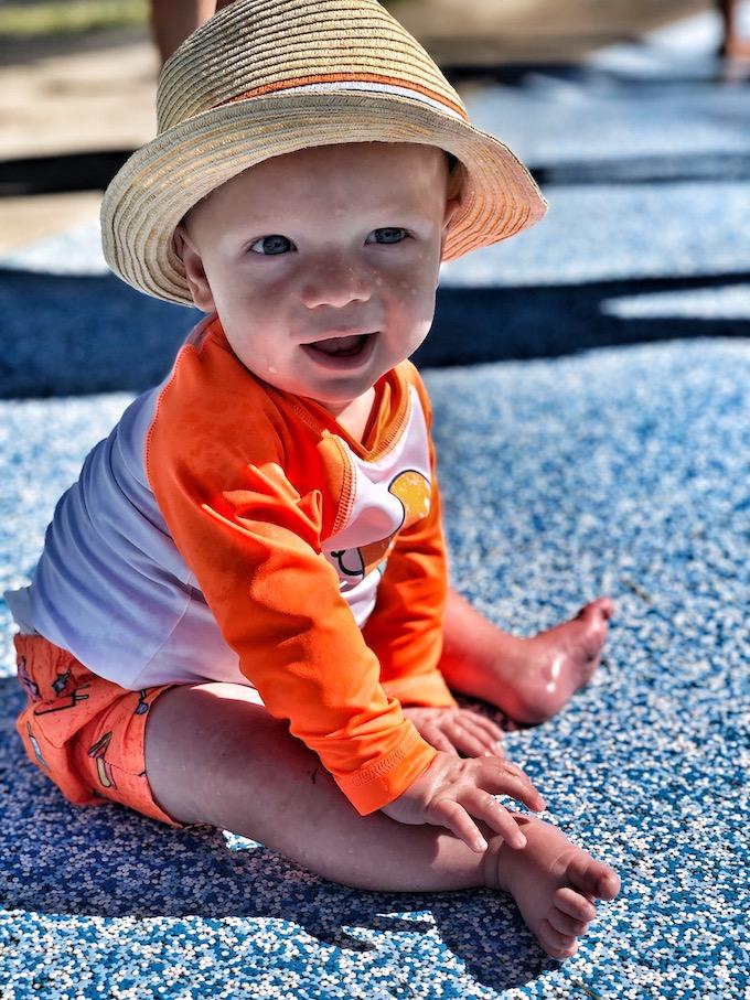 baby sitting at the splash pad