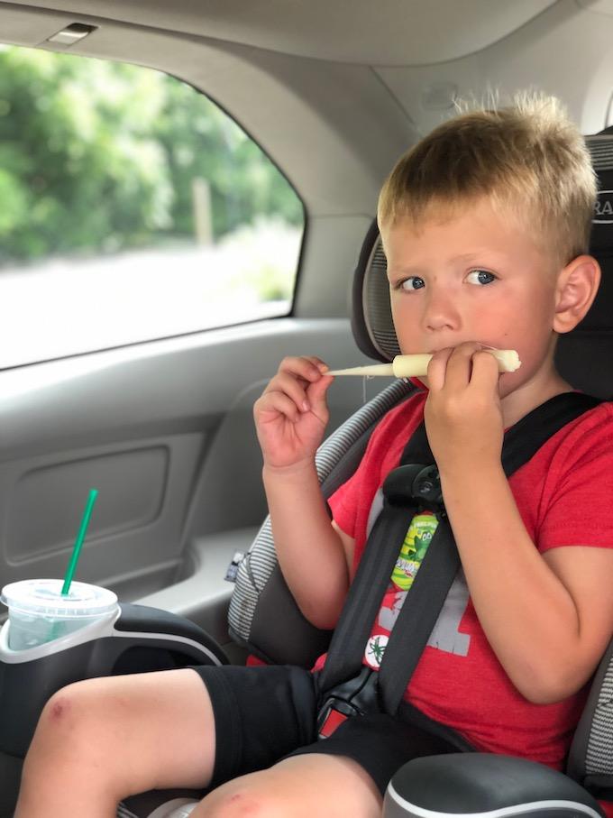 child eating string cheese in the car