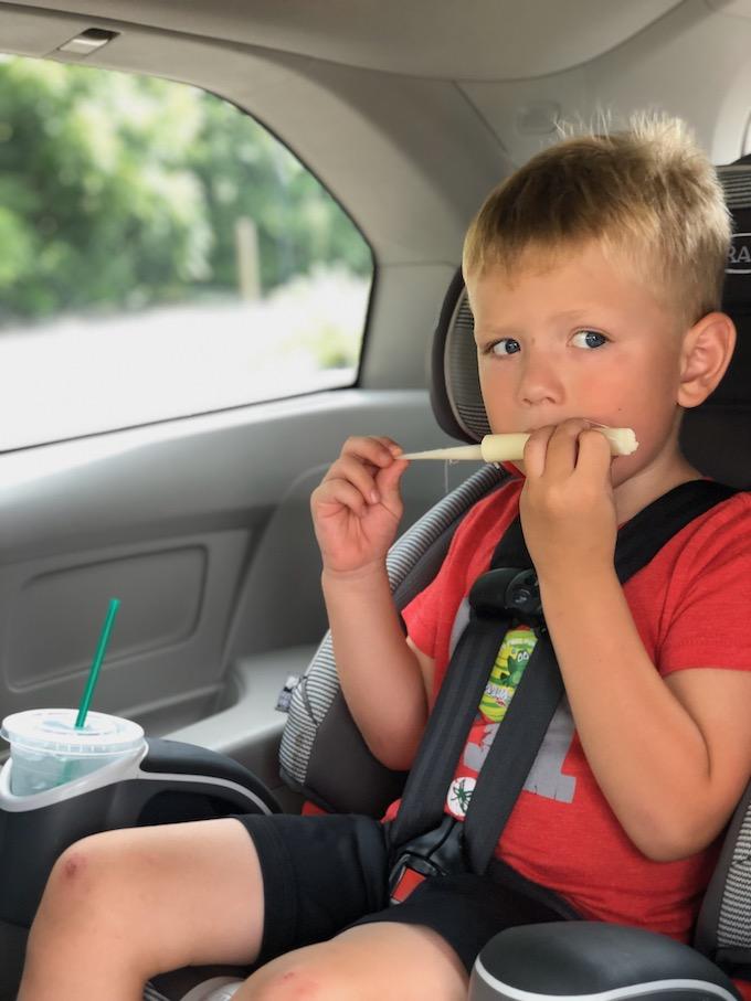 toddler eating cheese stick in the car