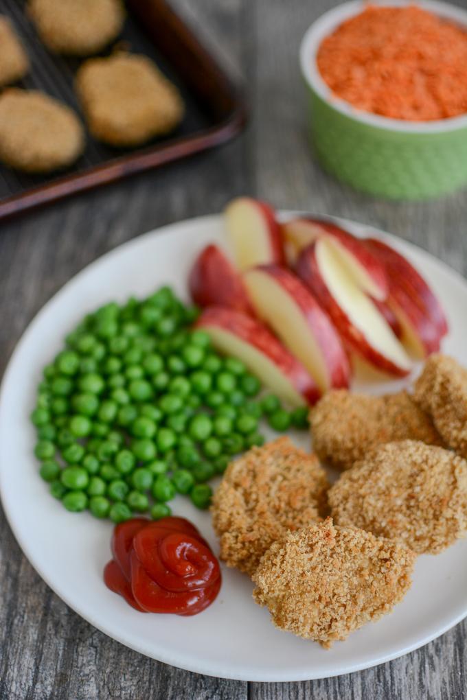 Red Lentil Chicken Nuggets with sliced apples and green beans on a white plate