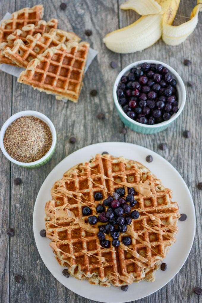 Overhead shot of Banana Flax Waffles topped with blueberries and peanut butter