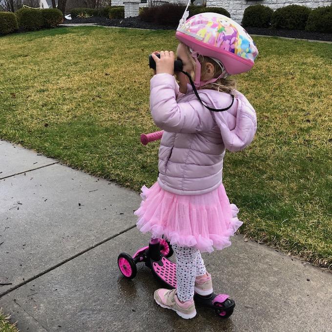 toddler on a scooter with binoculars