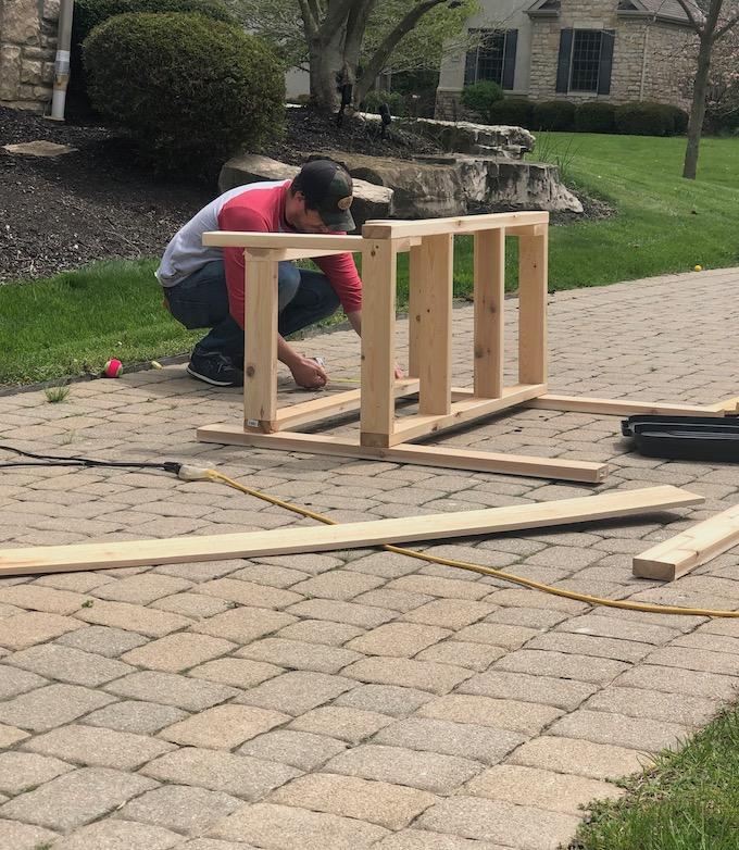 how to build a mud kitchen - man measuring for lower frame