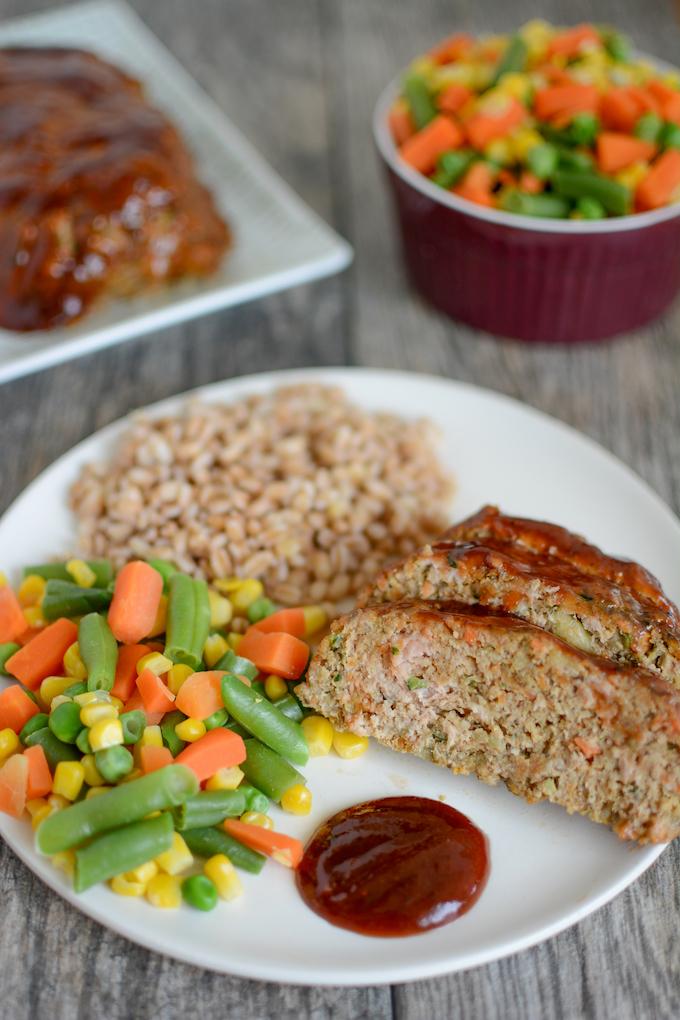 turkey meatloaf with vegetables on plate with steamed mixed vegetables and farro