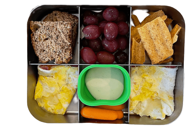 kids lunch with banana bread, egg wrap, carrots with ranch, sun chips and grapes