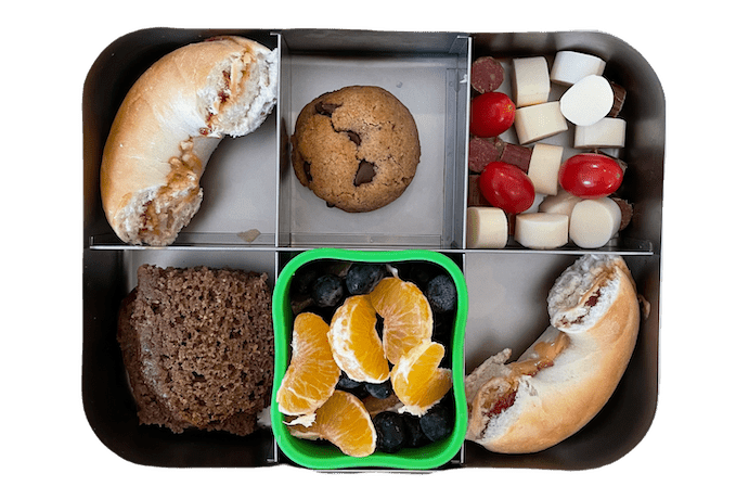 kids lunch box with peanut butter and jelly bagel, fruit salad, banana bread and cookie