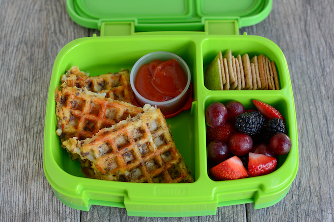 tater tot waffle in lunch box with ketchup, crackers and fruit